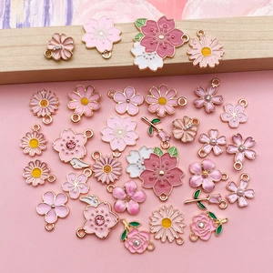 Flat lay of diverse pink enamel flower charms with gold edges and rhinestone details