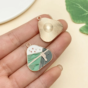 Detailed view of handmade enamel windmill pendant charm with polished gold texture back
