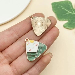 Detailed view of enamel and gold dragon boat festival Zongzi charms held in hand