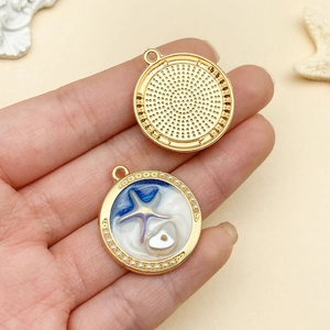 Macro shot of sea-themed enamel pendant with starfish and pearl details in gold finish