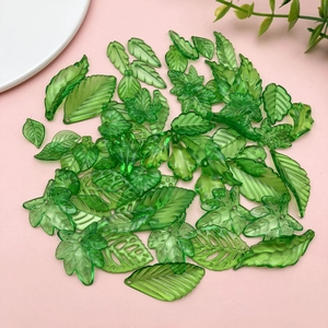 Detailed view of green acrylic leaf charms with intricate veins for DIY jewelry making