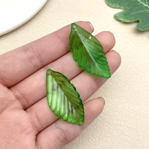 Detailed close-up of translucent green leaf pendants with delicate vein texture for DIY jewelry