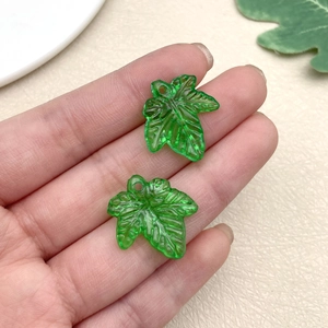 Detail of green acrylic leaf pendants held in hand showing size for DIY jewelry making
