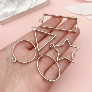 Silver geometric metal frames for DIY pendants held in hand with jewelry charms