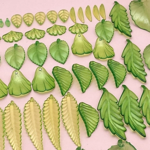 Mix aus Ginkgo- und grünen Blattanhängern aus Acryl für DIY-Schmuck auf rosa Grund