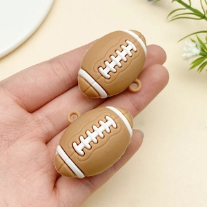 Detailed view of two miniature brown rugby pendants with white stitching and hanging holes