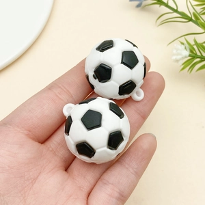 Miniature black and white soccer ball pendants with rings held in hand for DIY keychains