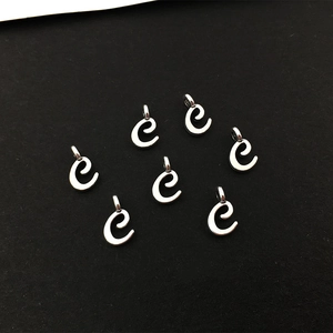 Makroaufnahme von sieben silbernen Alphabet-Anhängern 'e' für die DIY-Schmuckherstellung
