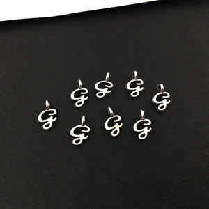 Makroaufnahme von acht silbernen Legierungs-Anhängern mit dem Buchstaben G für DIY
