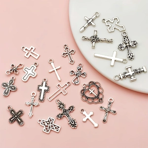 Détail de divers pendentifs croix en alliage argenté pour bijoux DIY sur fond rose