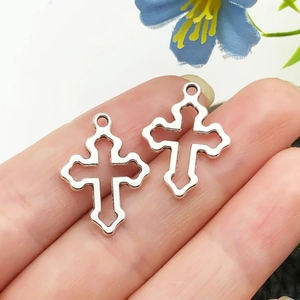 Détail de deux pendentifs croix évidés en argent tenus en main pour l'échelle