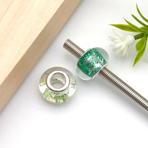 Detailed view of DIY green glitter resin large hole beads on a silver threaded rod