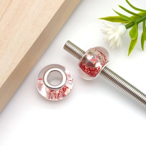 Detailed macro of resin large hole beads with red glitter and silver metal core