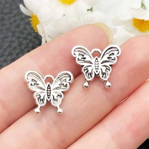 Dettaglio macro di ciondoli a farfalla in argento vintage con trama floreale complessa