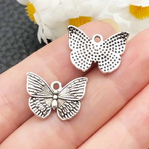 Dettaglio del ciondolo a farfalla in argento vintage con trama delle ali e foro di aggancio