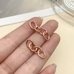 Pendientes de eslabones en oro rosa mostrados en la mano para tamaño y acabado