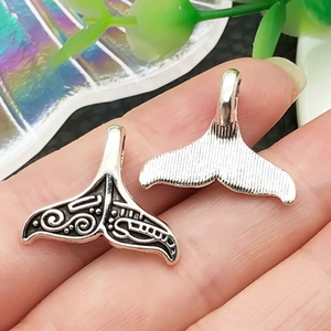 Detail showing front and back of whale tail pendants with retro black oil patterns