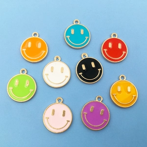 Flat lay of colorful enamel smiley face charms with gold plating on a blue background
