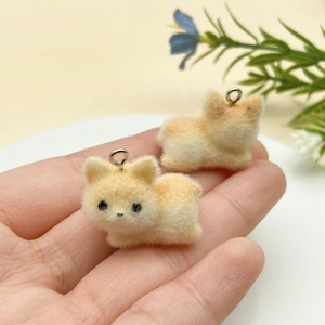 Close-up of mini flocked puppy charms with metal rings held in hand for DIY jewelry making