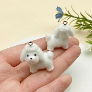 Close-up of cute white flocked puppy charms with silver rings held in hand
