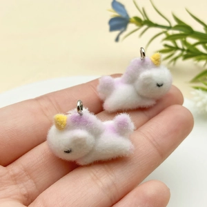 Close-up of cute flocked unicorn charms with purple details and metal rings for DIY crafts