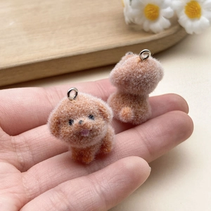 Close-up of cute flocked teddy dog charms with soft orange-brown texture and metal rings