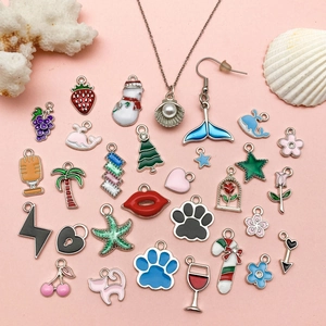 Assorted summer enamel charms set with fruit and marine motifs on light pink background