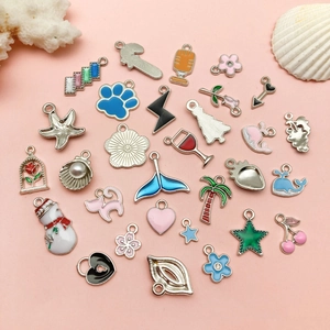Variety set of colorful enamel alloy charms with ocean, plant and winter motifs on pink background