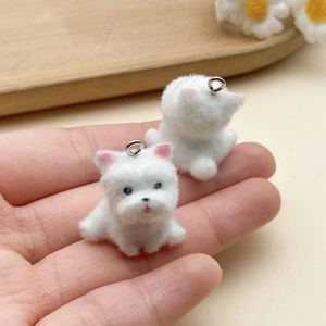 Miniature white flocked Westie dog charms with silver rings held in hand
