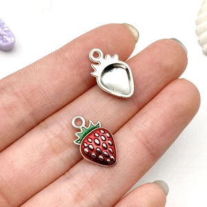 Macro detail of strawberry pendants showing red enamel finish and silver metal base
