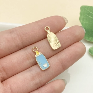 Primer plano de mini colgantes de biberón en esmalte azul y oro para creación de joyas DIY