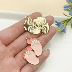 Detalle de colgante de abanico dorado y huella de bebé rosa para joyería DIY