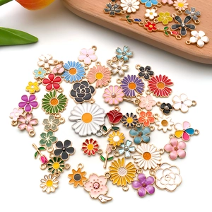 Assorted colorful enamel flower pendants with gold borders and tulips on a white background