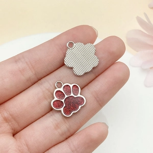 Vue macro des breloques pattes de chat à paillettes rouges montrant le recto et le verso