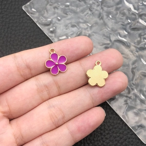 Detailed macro view of a purple enamel daisy pendant charm with a gold alloy base
