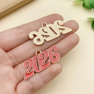 Vista detallada de dijes 2026 con textura de metal dorado y acabado de esmalte rojo