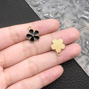 Detail of flower charm with black enamel front and brushed gold metal back for DIY jewelry
