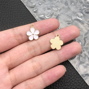 Detail of white enamel flower charms with gold alloy base and striped back texture