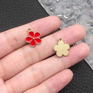 Detail of red enamel daisy charm with gold plating and textured metal back for DIY crafts