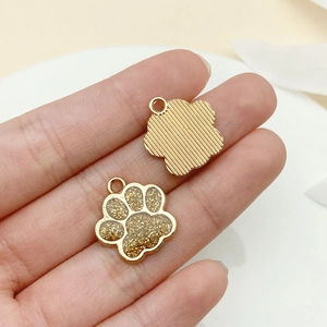 Gros plan du pendentif patte de chat doré avec détails pailletés et revers en métal texturé