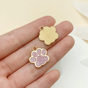 Détail macro du pendentif en forme de patte avec paillettes roses et finition dorée