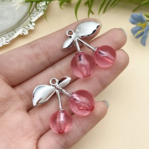 Detailansicht von rosa Harz-Kirsch-Anhängern mit silbernen Metallblättern für DIY-Schmuck