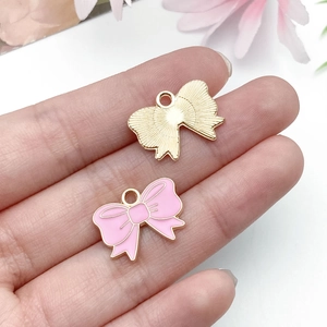 Detail of pink oil-dripped and gold bow charms with fine metallic textures for DIY jewelry