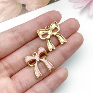 Detail of pink enamel bow pendant and gold alloy charm for DIY jewelry and necklaces