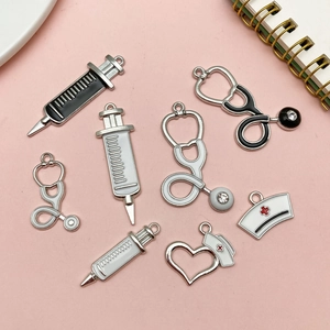 Flat lay of medical charms set with stethoscopes, syringes, and nurse hats on pink surface