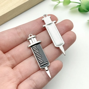 Macro detail of alloy syringe charms with scale textures for medical DIY jewelry
