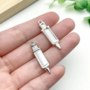 Detailed close-up of syringe alloy charms for DIY keychains in silver and white enamel