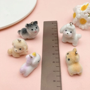 Detailed size comparison of flocked resin puppy and unicorn charms with a metal ruler