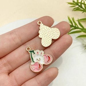 Détail de breloques émaillées lapin cerise avec dos doré pour création de bijoux DIY