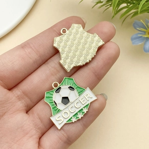 Détail du pendentif de football avec motif émail vert et revers en métal texturé doré